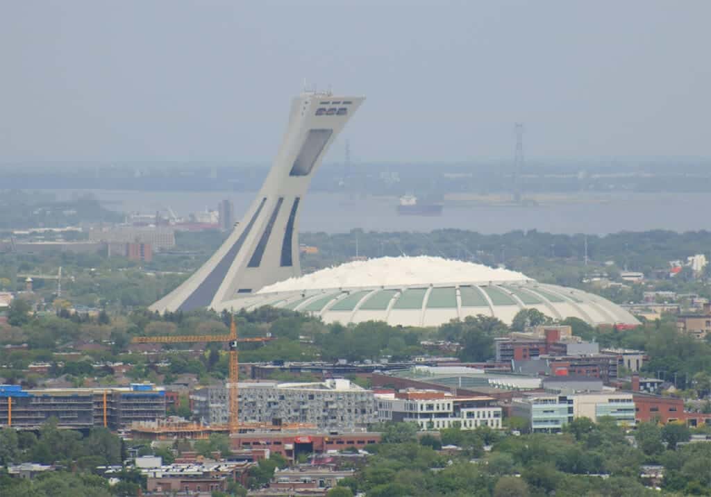 Aerial view of Montreal’s Olympic Stadium with surrounding neighborhoods, construction cranes, and greenery leading toward the St. Lawrence River. The city's mix of attractions and accessible layout makes many wonder, is Montreal walkable in spring—and this image shows just how navigable and compact key areas can be.
