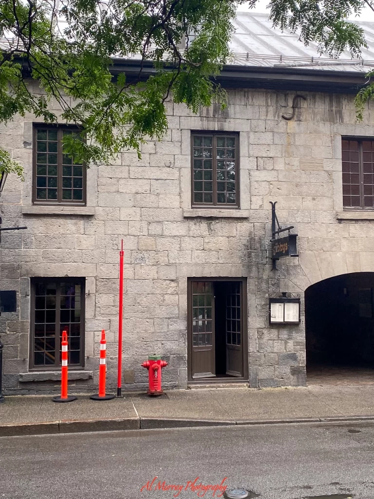 Exterior of Gibby’s Steakhouse in Old Montreal, set in a historic stone building with tall windows, a wooden door, and an arched entryway leading to the interior. The traditional architecture and easy-to-spot signage make it a welcoming and accessible location for a Gibby’s Steakhouse review for seniors.