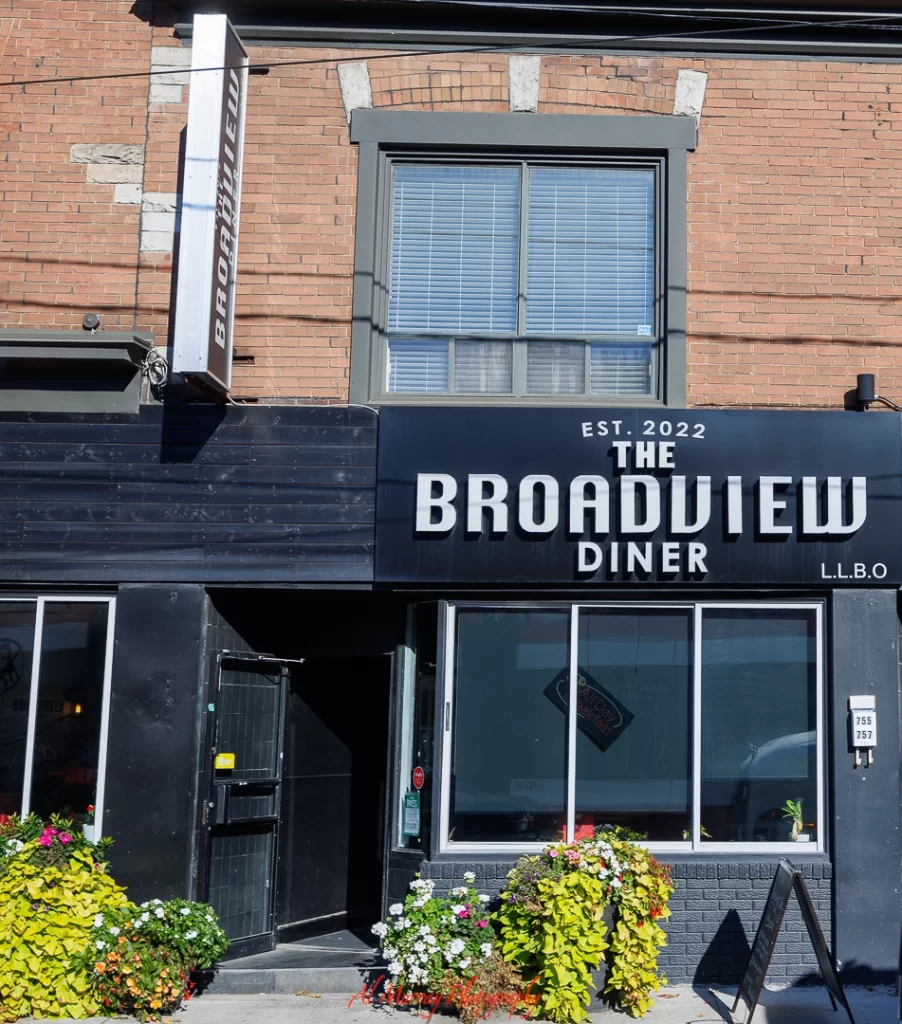 Close-up of The Broadview Diner’s entrance with bold signage reading "EST. 2022 The Broadview Diner" above large front windows and flower planters. The welcoming exterior hints at a cozy, senior-friendly breakfast spot in East Toronto