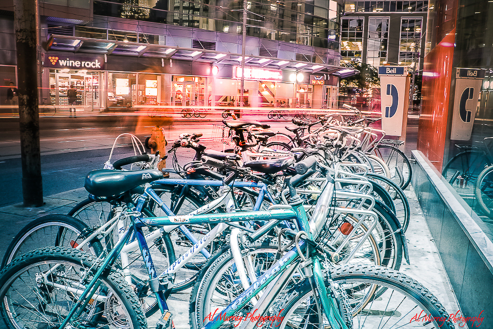 how to save money on toronto world cup 2026 hotels A row of bicycles locked at a bike rack on a busy Toronto street at night, with storefronts and light trails from passing traffic in the background. Cycling is a cost-effective and flexible option for getting to BMO Field during major events like the World Cup.