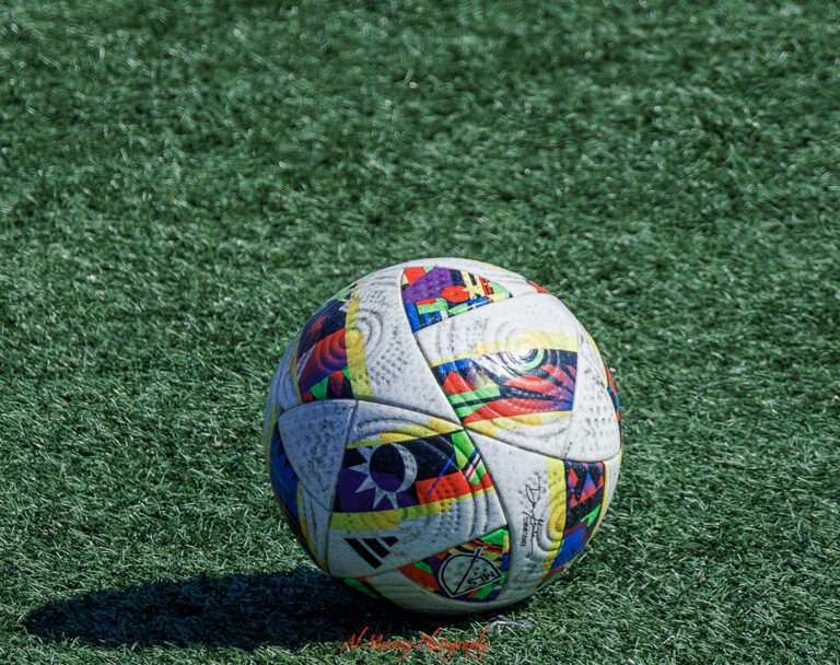 Colorful soccer ball resting on artificial turf under bright sunlight. This vibrant scene captures local recreation in the suburbs, a common feature near Vancouver budget stays