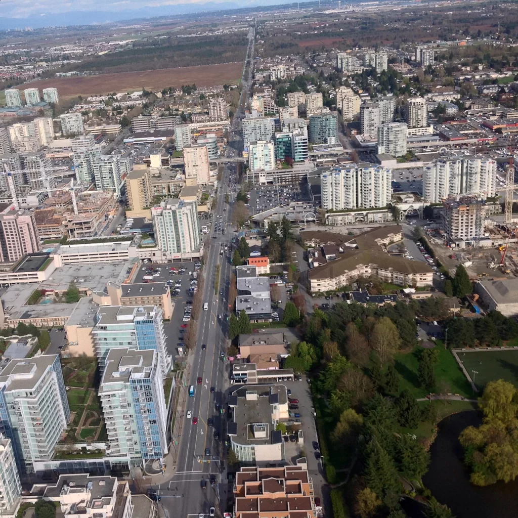 Vancouver budget stays suburbs Aerial view of a Vancouver suburb with mid-rise apartments, green spaces, and commercial buildings lining a major road. This neighborhood showcases the kind of well-connected, livable areas often home to Vancouver budget stays suburbs.
