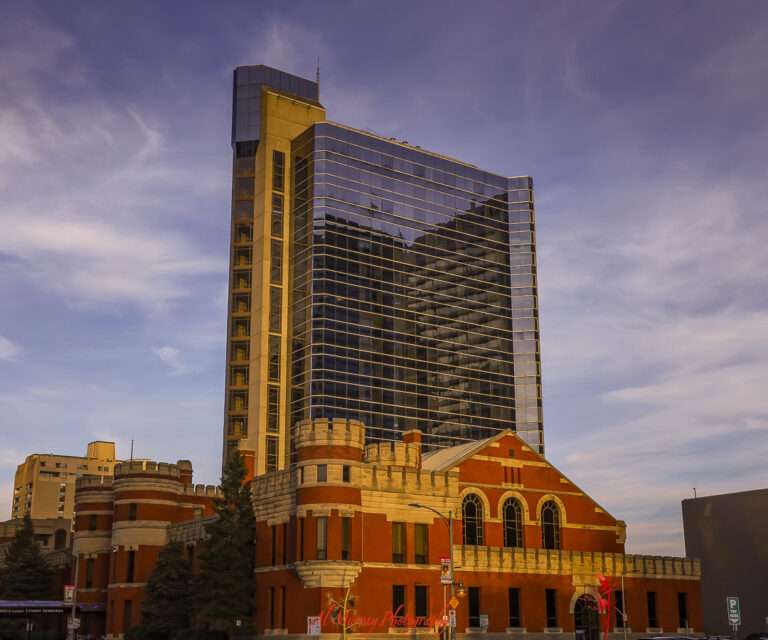 Striking contrast between a modern glass high-rise and a historic red-brick building with castle-like turrets, all bathed in golden sunset light. A dynamic urban scene often explored during day and night excursions from Toronto, blending history with contemporary city life.