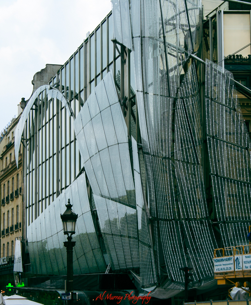 Modern glass and metal building facade in Paris with flowing, sculptural panels and a classic streetlamp in the foreground. This striking urban scene highlights the kind of architectural sightseeing tennis fans can enjoy while planning a tournament trip that blends sports and culture.