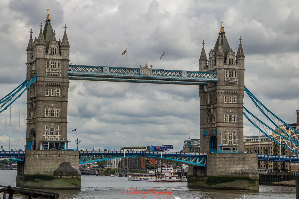Tower Bridge in London on a cloudy day, with pedestrians and vehicles crossing the iconic structure over the River Thames. A prime example of urban walkability, offering scenic routes and easy access to nearby historic and cultural landmarks.