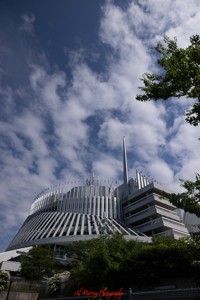 Striking architecture of the Casino de Montréal stands tall under a partly cloudy sky, framed by greenery at its base. This iconic spot adds a playful and upscale option to any Montreal Valentine's Day itinerary for couples looking for a fun night out.
