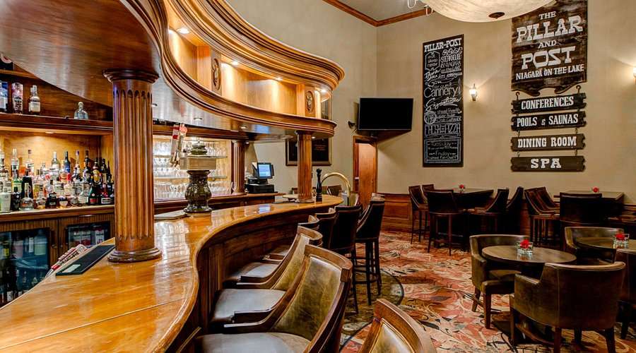 Warm, inviting hotel bar with wooden counters, leather chairs, and softly lit décor, located at The Pillar and Post in Niagara-on-the-Lake. Ideal for a solo Valentine’s Day outing in Canada, this cozy space offers a relaxing atmosphere for enjoying a quiet drink or meal alone.