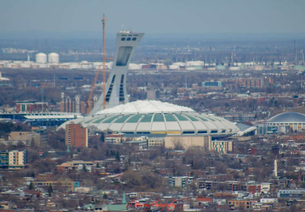 Aerial view of Montreal’s Olympic Stadium with its iconic inclined tower and snow-covered roof, surrounded by the city’s urban landscape. Visiting this landmark solo offers access to the Montreal Tower Observatory and nearby attractions like the Biodome and Botanical Garden—ideal stops when exploring things to do alone in Montreal