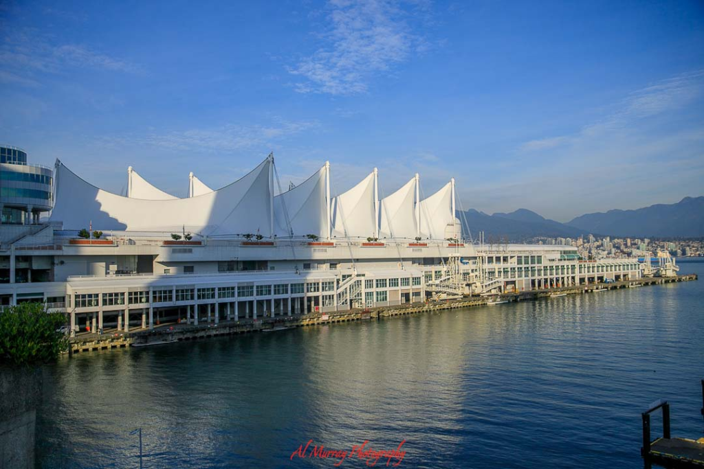 where to watch the world cup 2026 in vancouver Waterfront view of Canada Place in downtown Vancouver with its iconic white sail roof stretching along the harbor and mountains in the background under a clear blue sky. The scenic setting highlights a prime location for downtown Voncouver World Cup watch parties, offering open spaces and a lively atmosphere near the city’s main attractions.