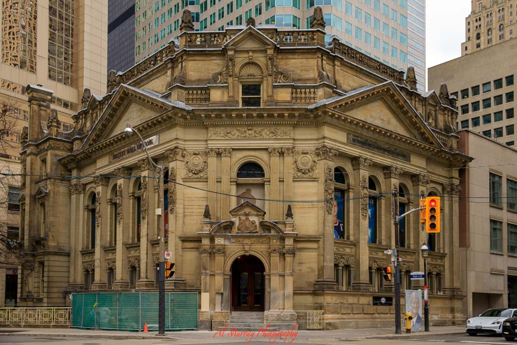 where to watch the world cup 2026 in Toronto Historic sandstone theater building in downtown Toronto with ornate columns, arched windows, and detailed carvings on the facade, surrounded by modern high rise office towers at a busy street corner. The grand exterior suggests a cultural venue or public gathering space to Watch World Cup 2026 in Toronto without tickets, offering an alternative atmosphere beyond the stadium.