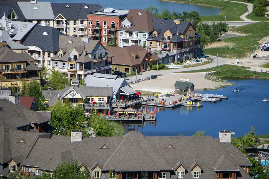 Colorful lakeside village with shops, restaurants, and a busy dock filled with paddle boats and people enjoying the water, making it a lively stop along one of the best road trips from Toronto.