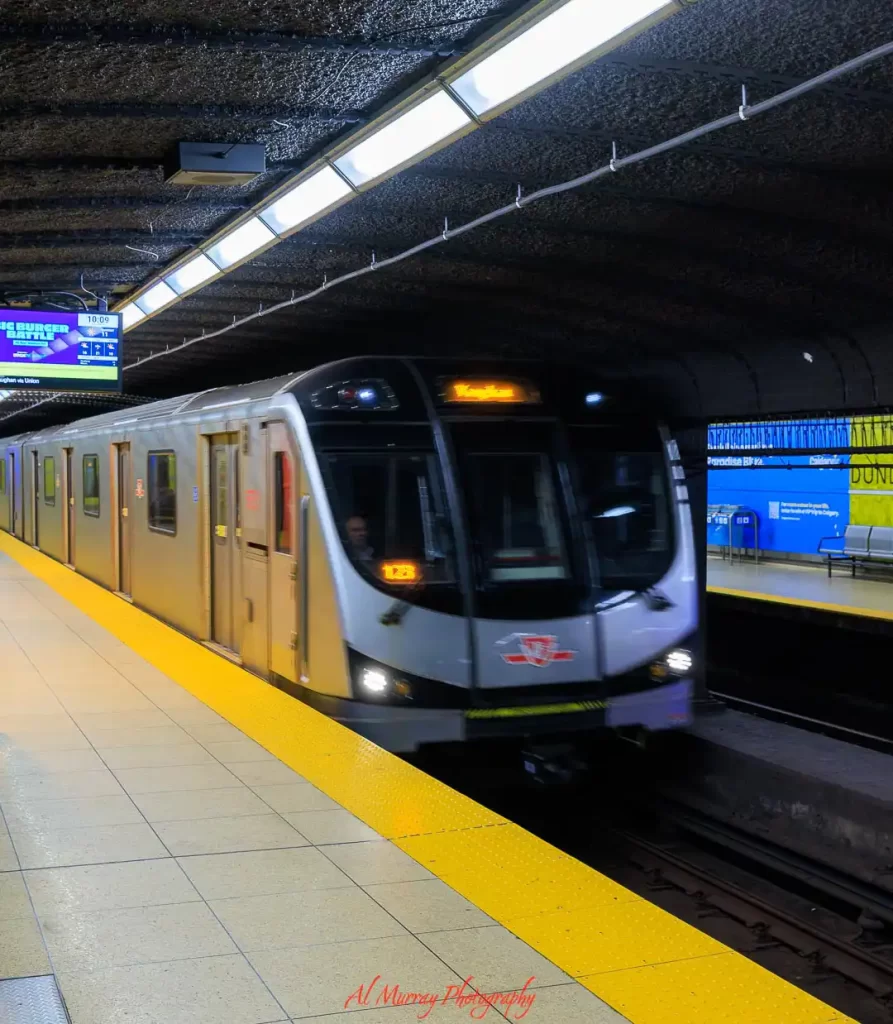 Toronto subway train arriving at an underground station with yellow platform edge and tiled walls, highlighting easy public transit access for where to stay in Toronto without a car.