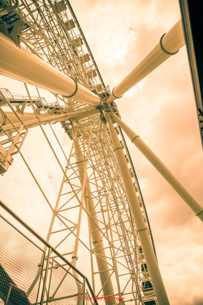Looking straight up through the white steel supports of a large Ferris wheel against a warm golden sky in Montreal. The towering attraction shows one of the city experiences travelers may want nearby when deciding where to stay in Montreal for mature travellers.