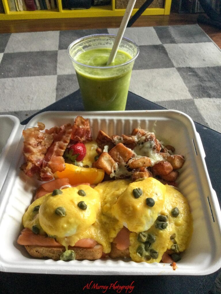 toronto hotels with breakfast included A hearty breakfast tray features eggs Benedict with smoked salmon and capers alongside bacon roasted potatoes fruit and a bright green smoothie. The generous spread shows the kind of breakfast travelers may be looking for when comparing affordable Toronto hotels with breakfast included. The red watermark reads "Al Murray Photography".