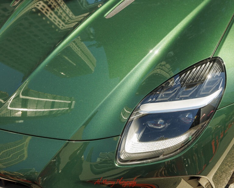 Close up of a metallic emerald green luxury sports car with sleek LED headlights and reflections of surrounding buildings on its glossy hood. Spotting luxury cars while exploring the upscale neighbourhood is one of the Bloor Yorkville things to do in Toronto.